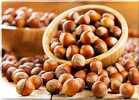 There are many hazelnuts in and around two bowls.